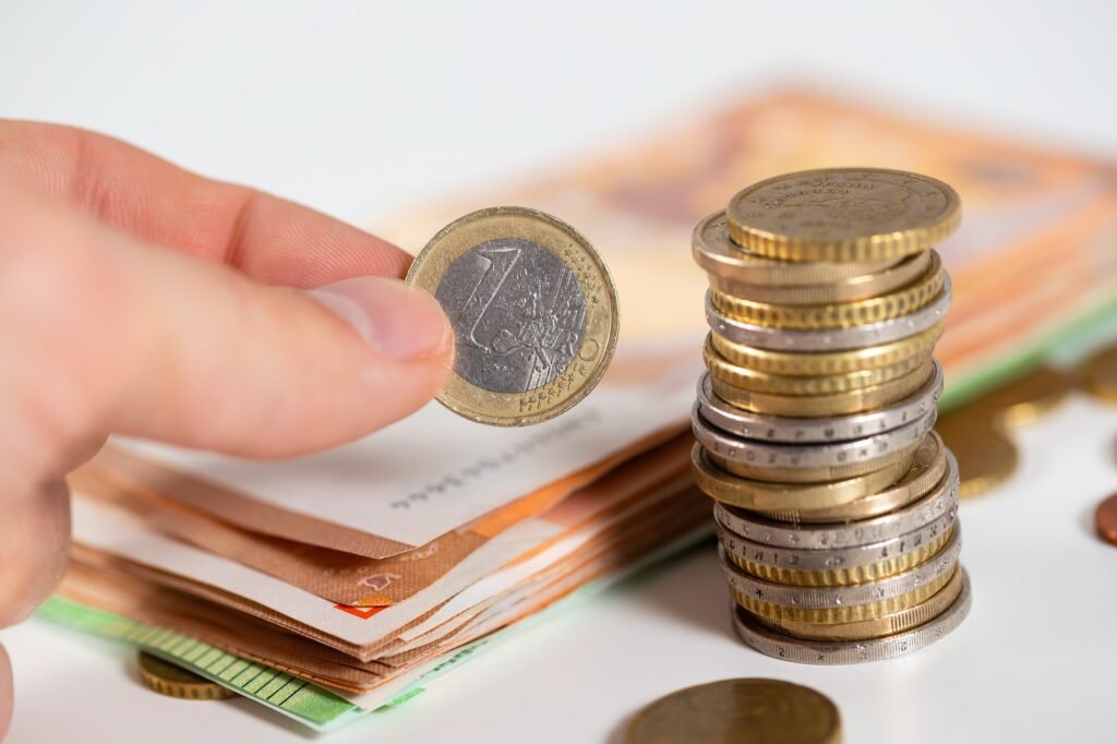 Human hand putting one euro to the stack on white table